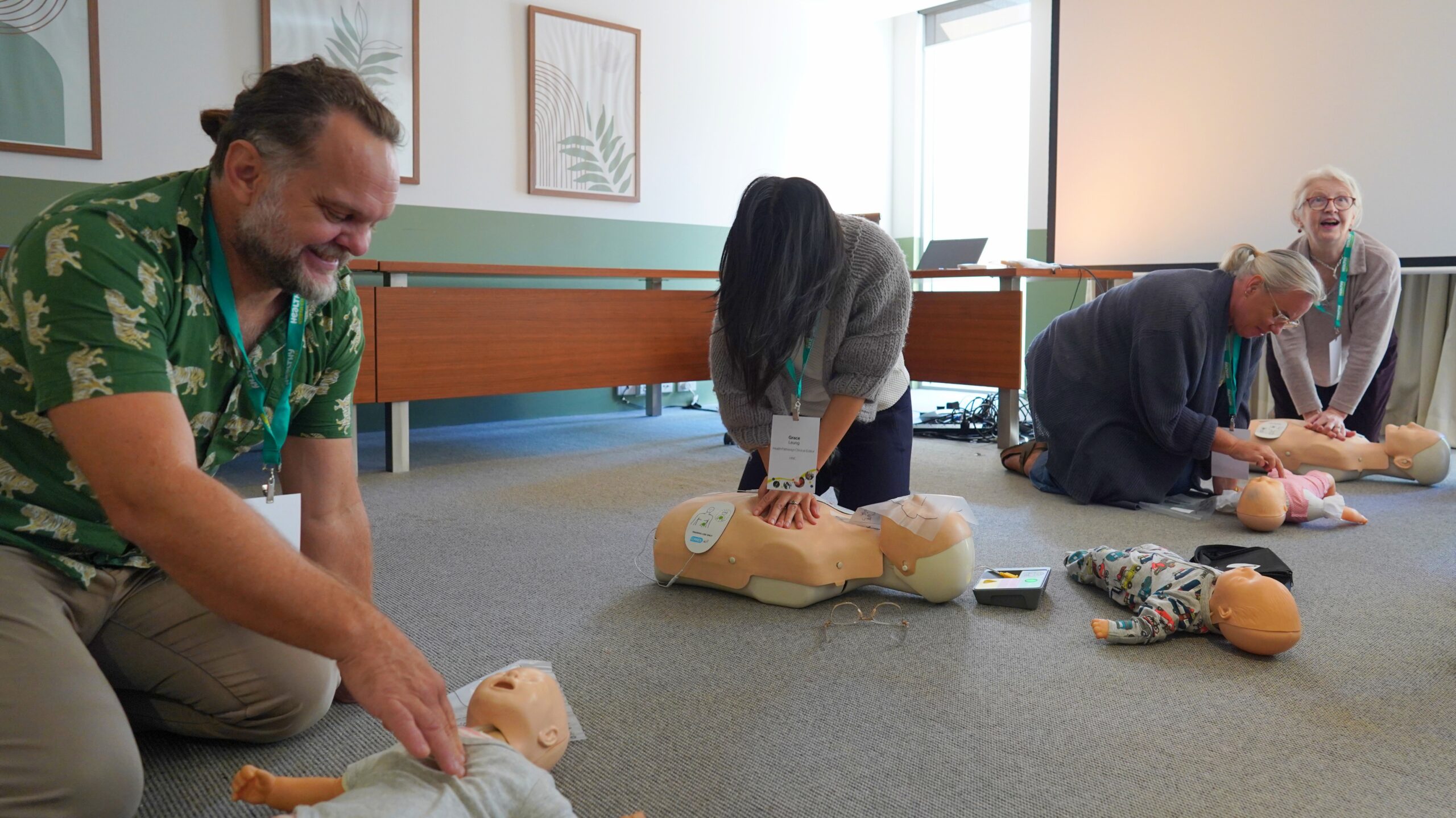 Four healthcare participants practising CPR chest compressions on adult and infant manikins during Advanced Life Support training.